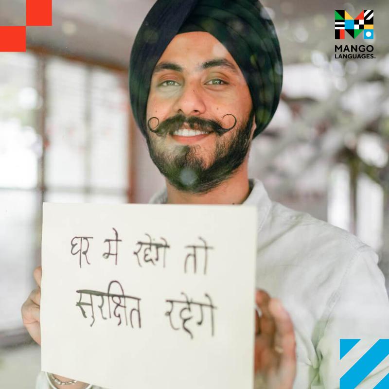 A man holding a sign written in Hindi