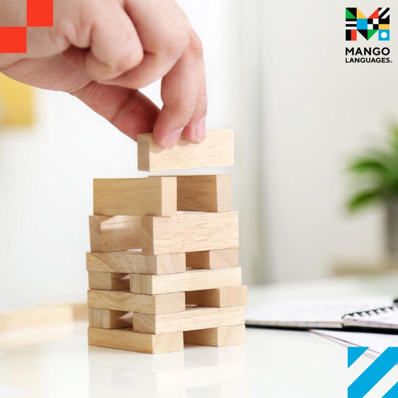 A hand stacking Jenga blocks on top a table